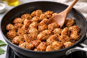cooking diced chicken in skillet for chicken and rice recipe