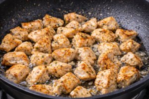 Golden brown chicken pieces cooking in a skillet for creamy garlic chicken pasta