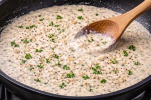 Garlic parmesan cream sauce simmering in a skillet for creamy garlic chicken pasta