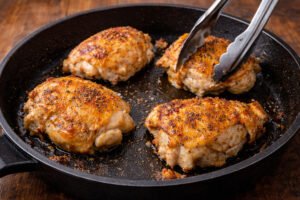 Chicken thighs searing in a skillet for honey garlic chicken and rice