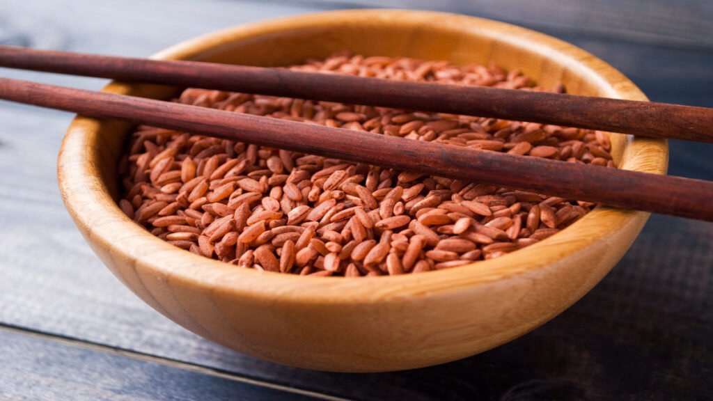 Raw red rice with firm grains and earthy texture in a wooden bowl with chopsticks