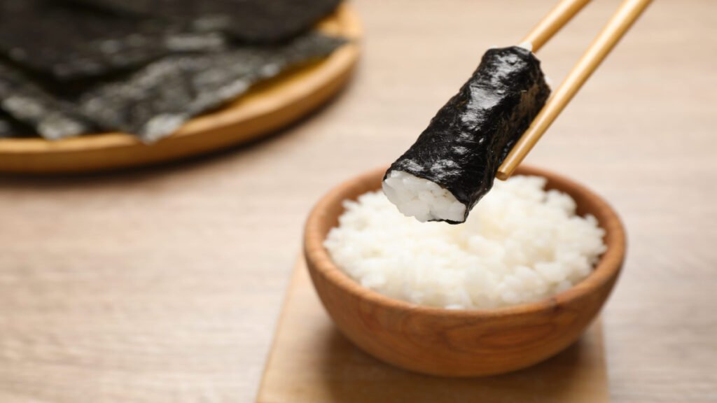 Sticky sushi rice with glossy texture wrapped in nori sheet and in a bowl