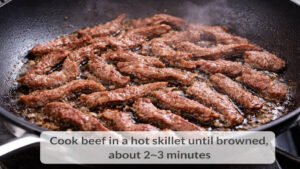 Thin sliced beef cooking in a hot skillet for beef and pepper stir fry