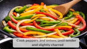 Sliced bell peppers and onions cooking in a skillet for beef and pepper stir fry