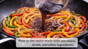 Savory stir fry sauce being poured into a skillet with peppers and onions