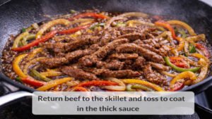 Cooked beef returned to the skillet with peppers onions and sauce for beef and pepper stir fry
